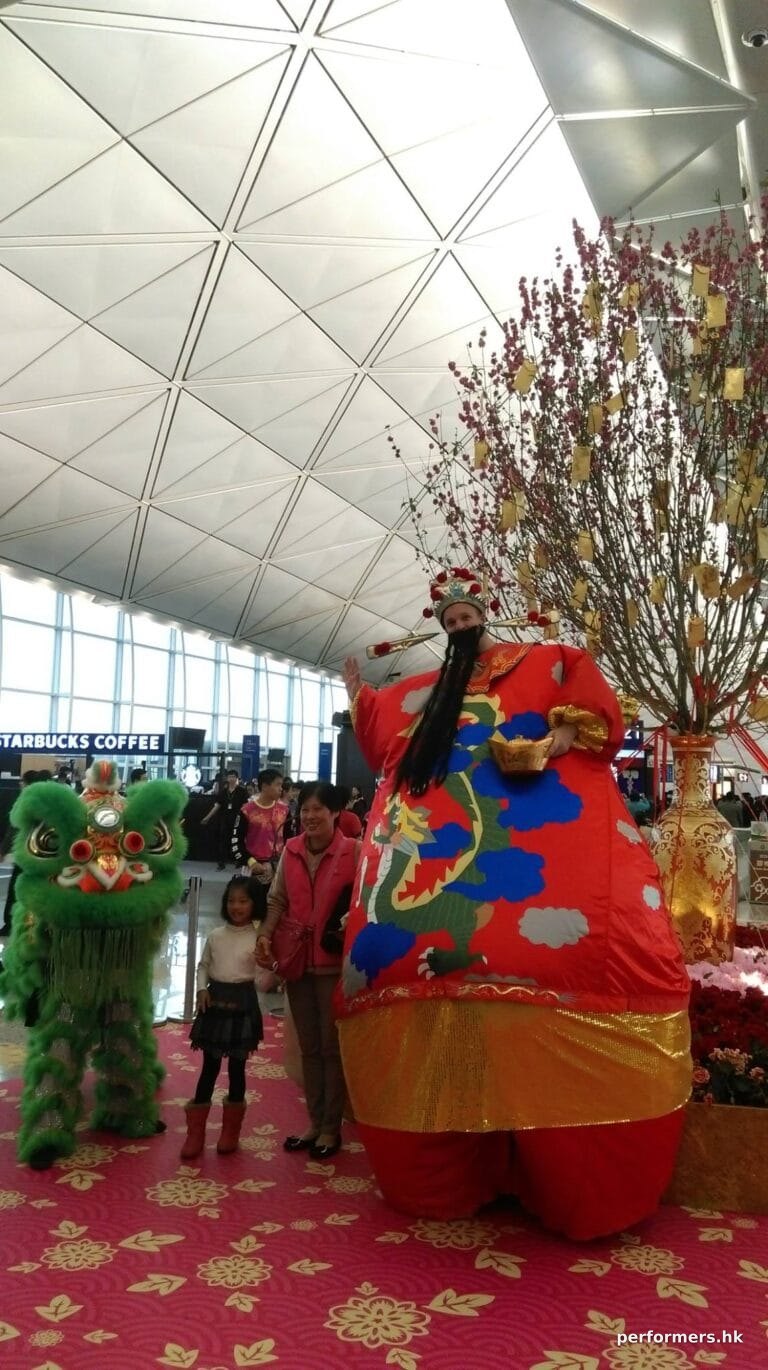 HK stilt-walker in giant inflatable Choi Sun costume at airport Chinese New Year event