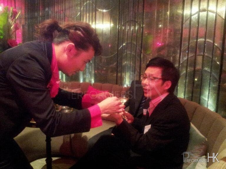 Roving magician performing coins trick to CEO at DBS Hong Kong cocktails event