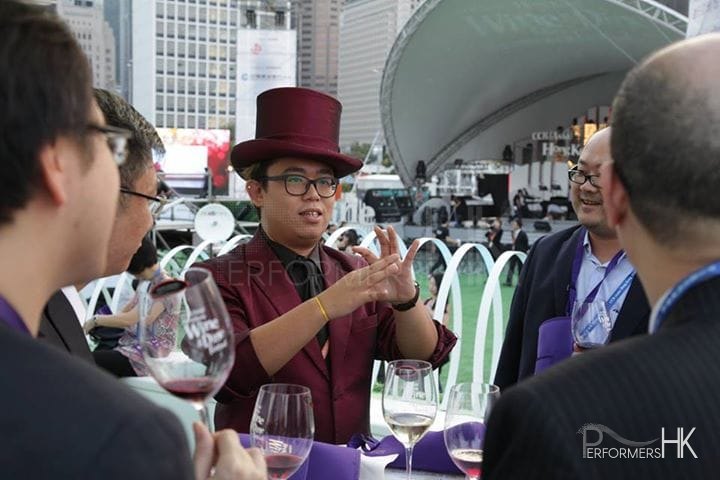 Magician in purple suit with a purple top hat performing table magic to four gentlemen at Hong Kong Happy Valley Races