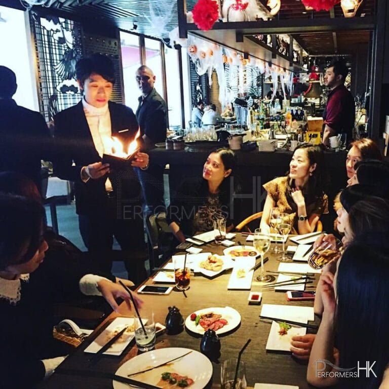 Magician performing roving fire magic to ladies at a Hong Kong restaurant