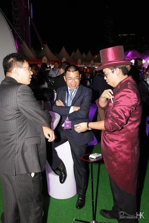 HK roving magician performing to two gentlemen at a racing event