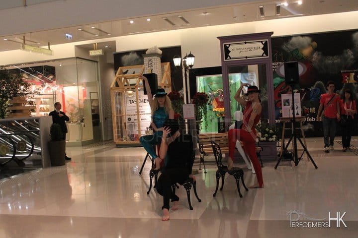 Three dancers in black, blue and red and wearing hats dancing in K11 mall