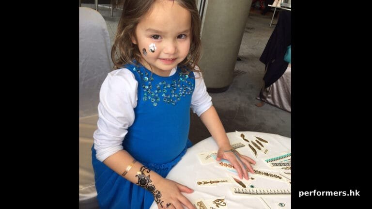 A little child having temporary henna tattoos on her both hands and face at a kids birthday party