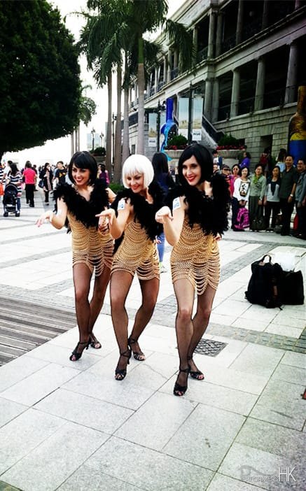 3 burlesque dancers posing in front of on-looking crowd