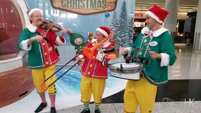 Three walk around musicians playing the violin drum and trombone at the HK Airport