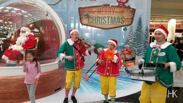 Three strolling musicians playing the violin drum and trombone at the HK Airport nest to santa in a globe