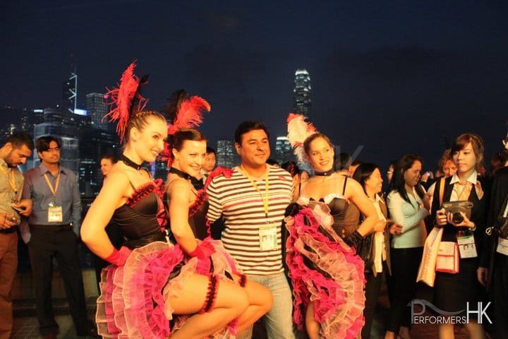 3 dancers with business person taking a photo with skyline of hk