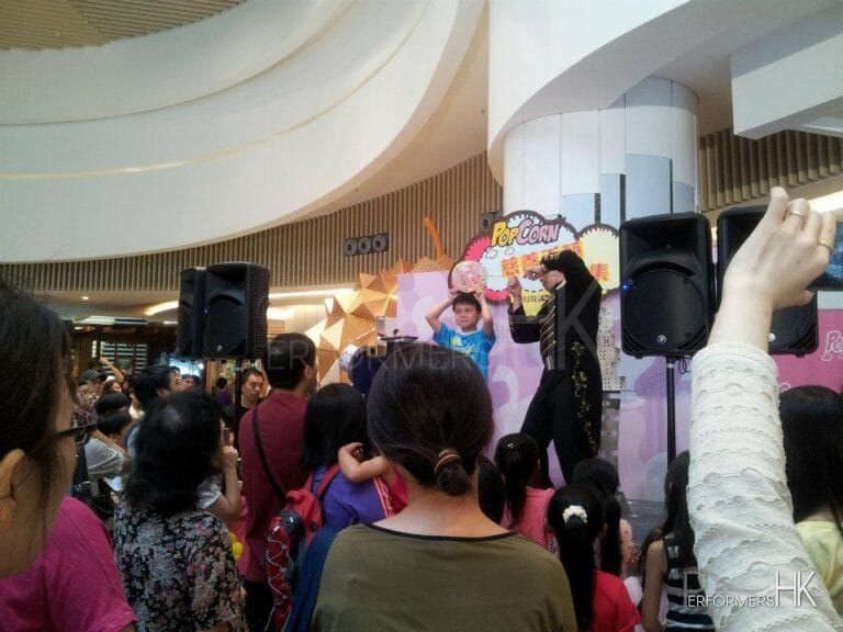 Magician in HK performing needle through a balloon magic trick on stage with a child audience on stage at Popcorn mall
