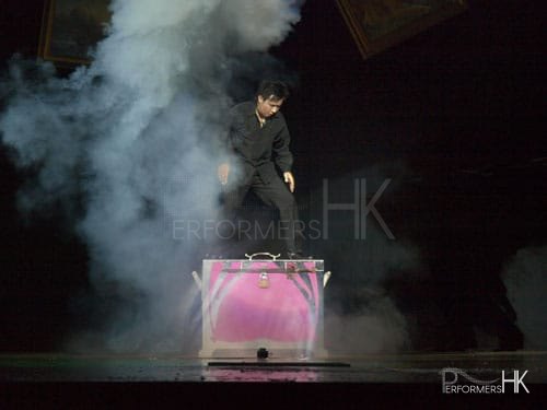 Magician standing on a huge pink box performing stage magic at a corporate annual dinner