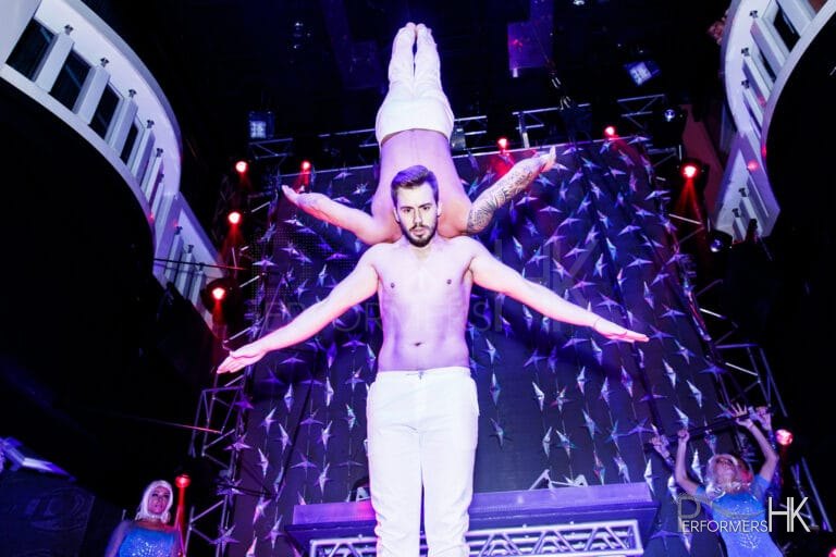 Two adage performers performing duo act at a corporate club event,one of the Performer upside down and holding by other performer with his shoulder only
