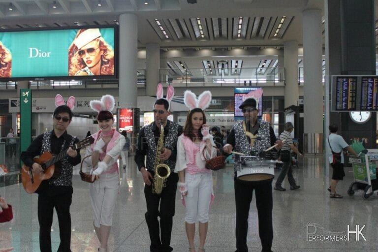 Three musician wearing bunny ears and sparkles vests , performing Easter songs with two models who dress as Easter bunny at the Hong Kong airport