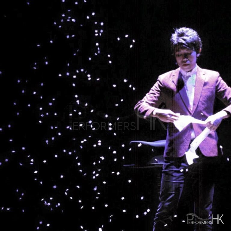 Magician in HK performing stage magic snow storm with white paper at corporate event.
