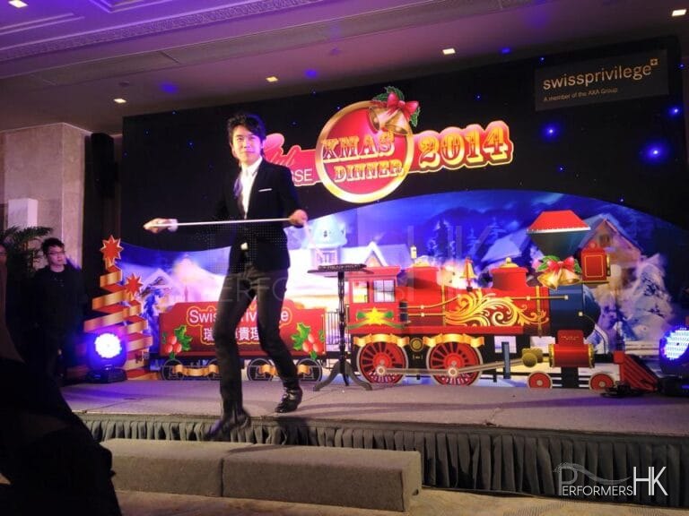 Magician performing stage magic with rope in front of a train backdrop at Hong Kong Swiss Privilege Christmas Dinner