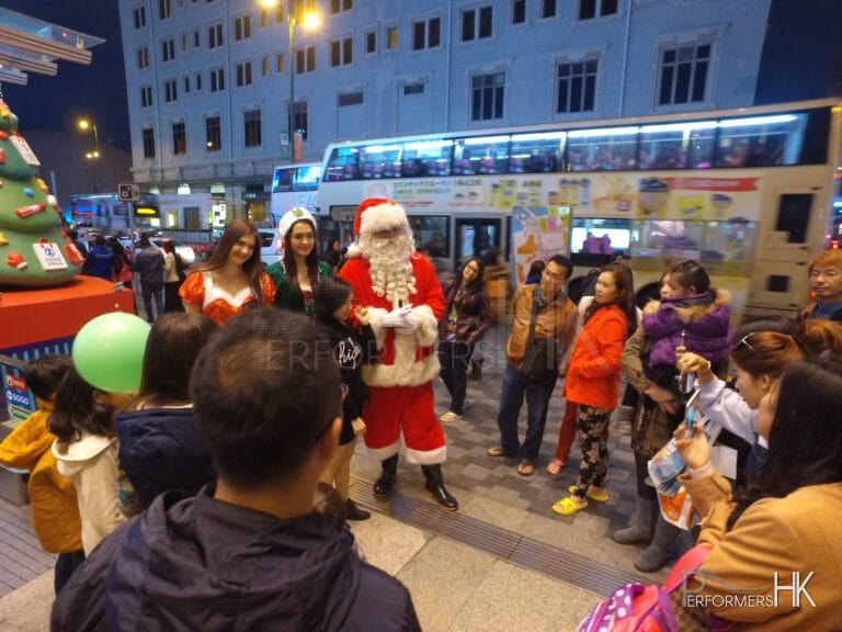 HK models and performer dress as Santa ,Santa girl and Elf standing outside Hong Kong greeting and photo taking with the guests at a Christmas corporate event.