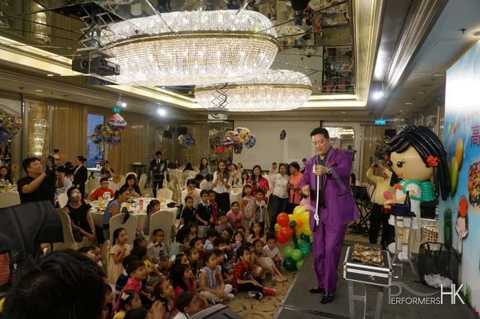 Magician on a stage doing a rope magic trick for kids in a hotel ballroom