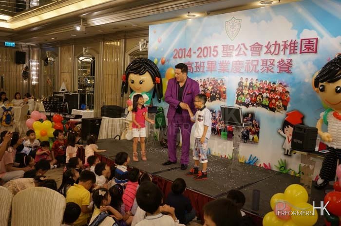 Magician performing magic with two audience helper at a corporation school event