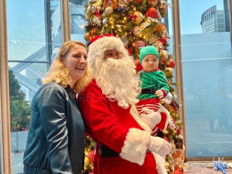 santa with elf baby in front of xmas tree