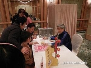 The Hong Kong bird fortune telling master explaining the card to five ladies at a corporate event