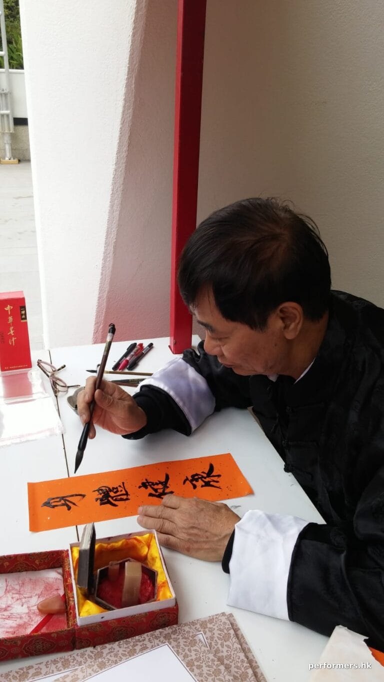 hong kong artist in traditional costume working on auspicious writings