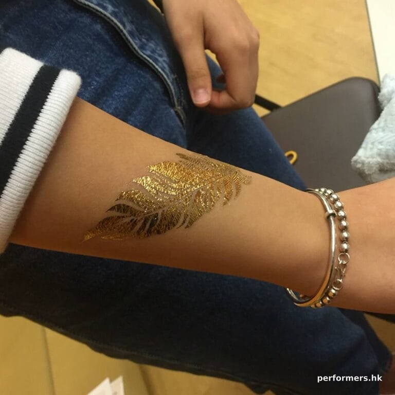 A guest choose a leaf shape gold tattoo on her hand at a school fun day event