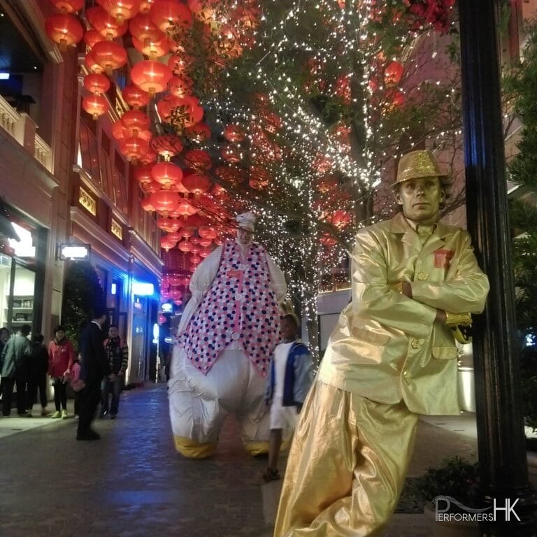 Golden statue leaning on lamp post with Giant Easter Bunny standing background