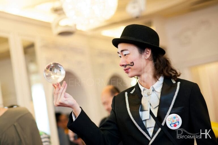 Contact juggler in HK wearing clown make up and costume performing with a crystal ball at a annual dinner