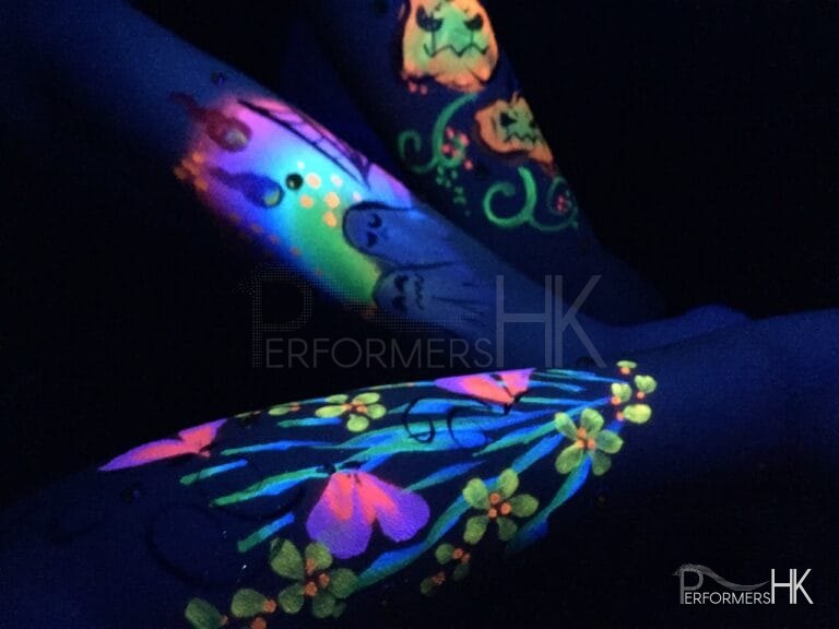 HK face painter draw a painting on hands with UV paint , the paintings are glowing under UV light at a corporate Halloween event