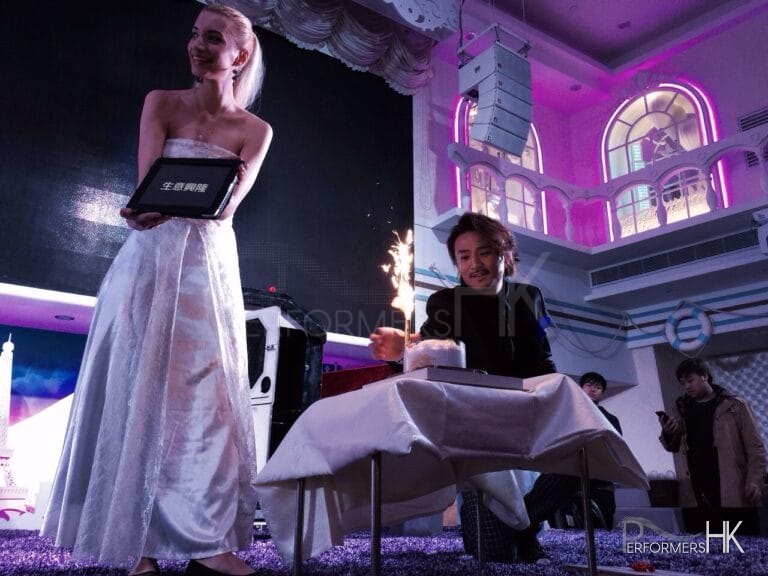 Magician in HK performing stage magic with birthday cake on the table to wich the company CEO happy birthday and his assistant holding a tap with words , wish your business success, at a corporate annual dinner and CEO birthday dinner