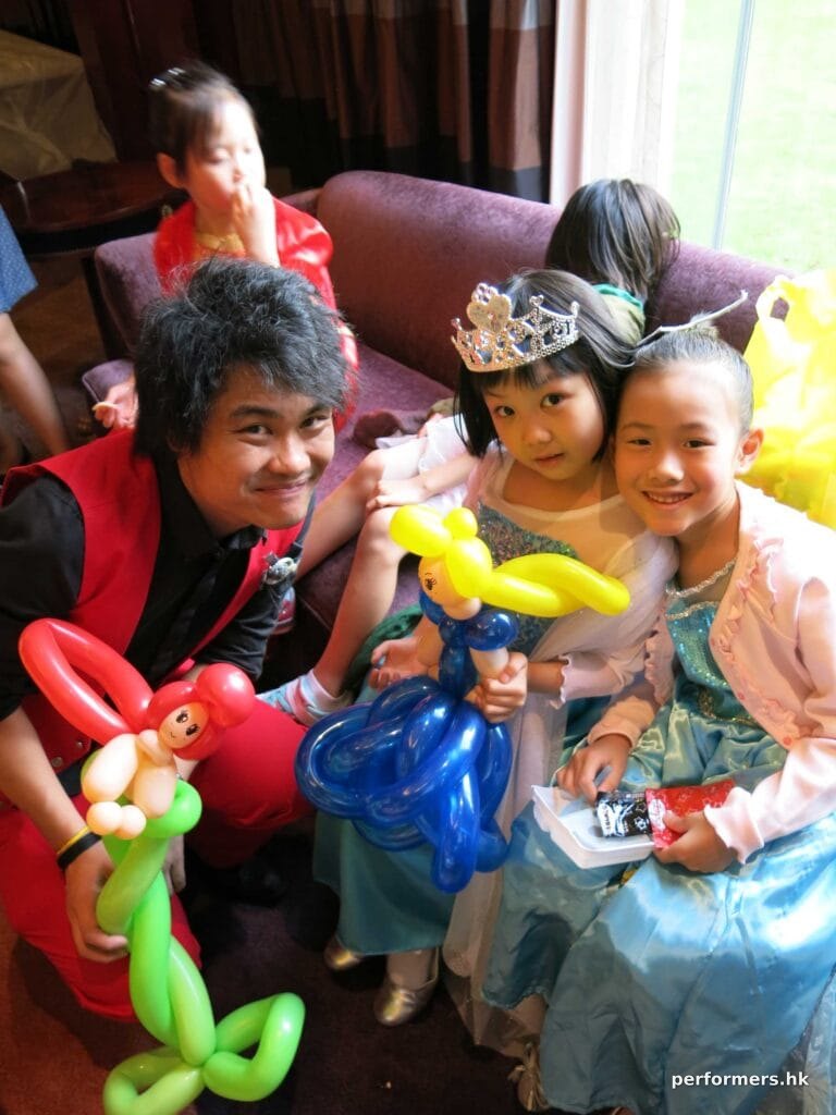 Roving Balloon artist in HK twisted two princess balloons for two children dressed in a Elsa costume at a kids birthday party