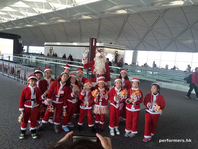 santa clause at hong kong airport with children in red santa costumes