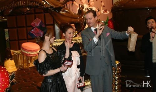 Magician performing stage magic vanishing and appearing wine bottle trick with Hong Kong celebrity at Chocolate Trail exhibition in Harbour City