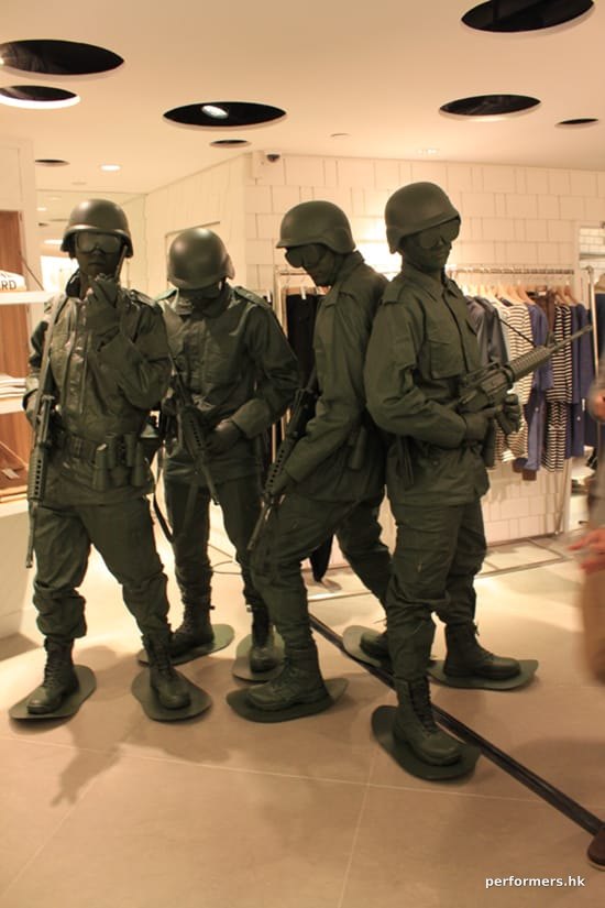 Four human living statue toy soldiers standing in a clothing shop
