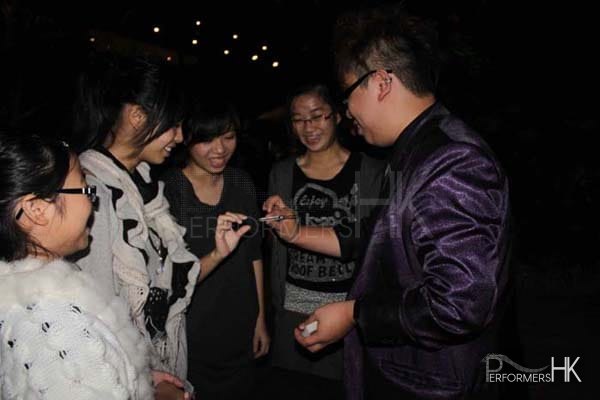 Hong Kong magician performing roving magic to four girls standing