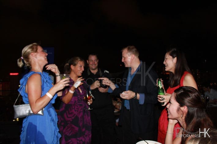 Hong Kong roving magician performing card magic trick to the lady in purple dress who holding a card at a corporate cocktails event