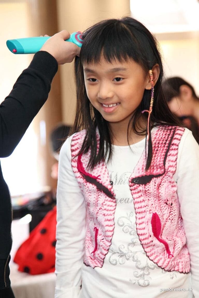 A little girl getting second braid wrap with a colorful string at a school event