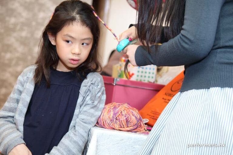 A lady wrapping the girl hair to braid with a little string machine at a corporate children event
