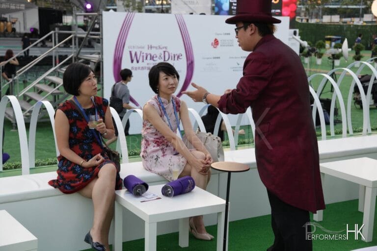 Roving magician at an exhibition in Hong Kong preforming a card trick to two girls