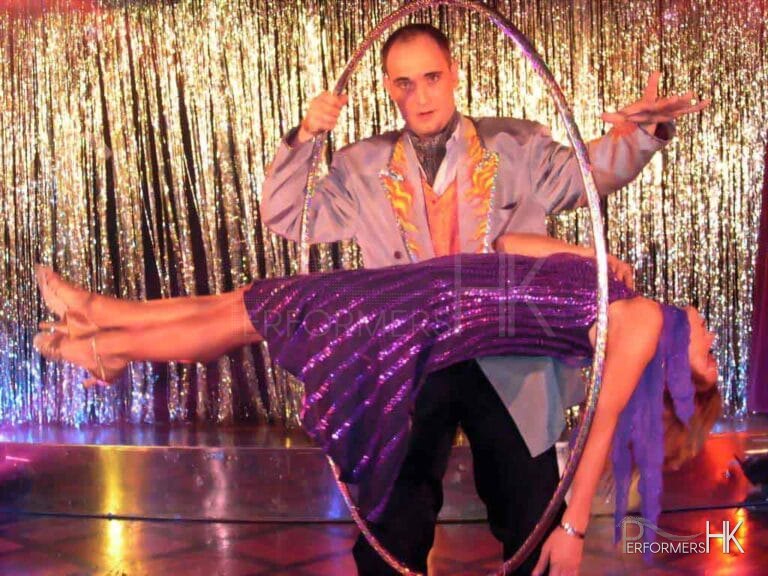 The beautiful lady is levitating and the magician in HK is holding a huge ring to show the audience there is no wires to keep the lady in the middle of the sir at a company function