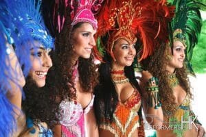 4 dancers in blue, pink, orange and green samba costumes
