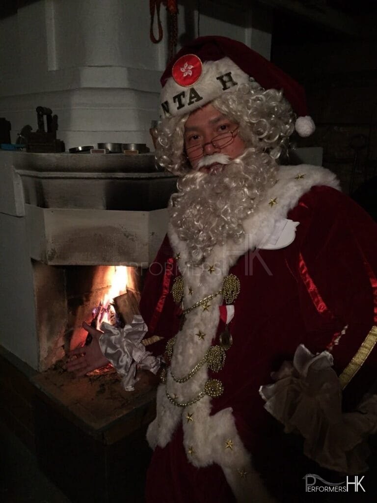 Chinese Santa Mario by the fire place staying warm in maroon colored santa suit