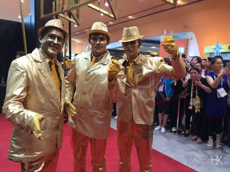 Three Hong Kong statue performers in gold costume at an annual event.