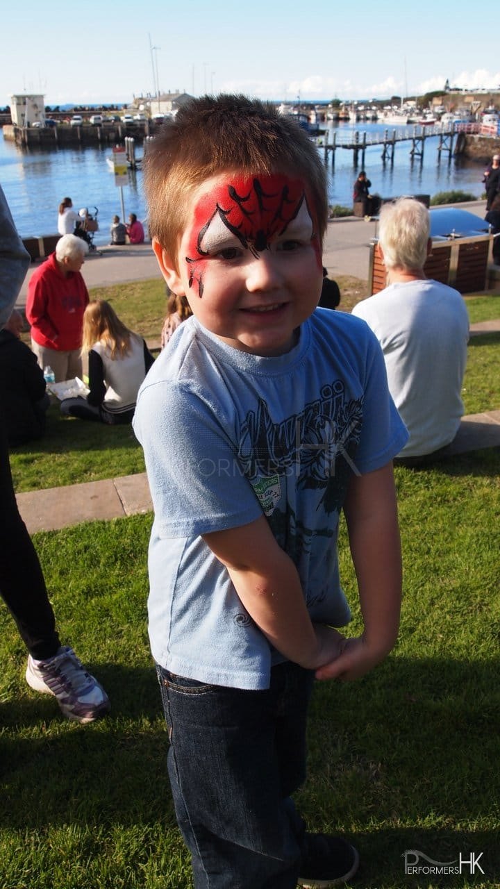 A little boy at a outdoor corporate function became a Spiderman after he got a spider man paint from a Hong Kong face painter