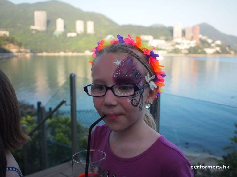A purple sparkle half-face face paint done by a Hong Kong face painter at a family fun day