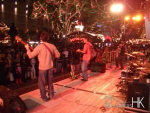 Band onstage at an outdoor event with Santa grotto in background