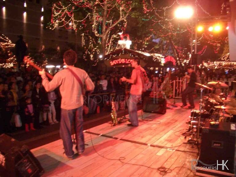Band onstage at an outdoor event with Santa grotto in background