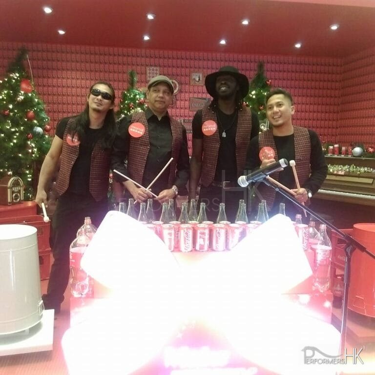 Four trash / bottle drummers have photo taken in front of the props