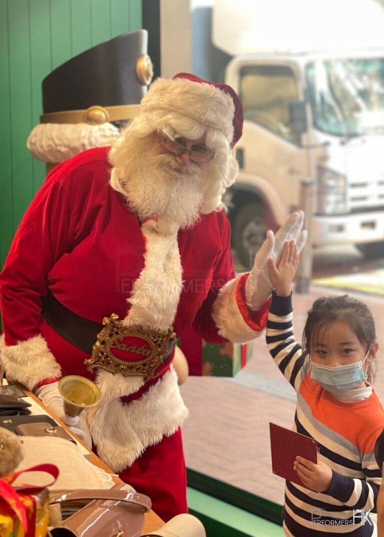 hong kong santa martin greeting litte girl high five in red costume