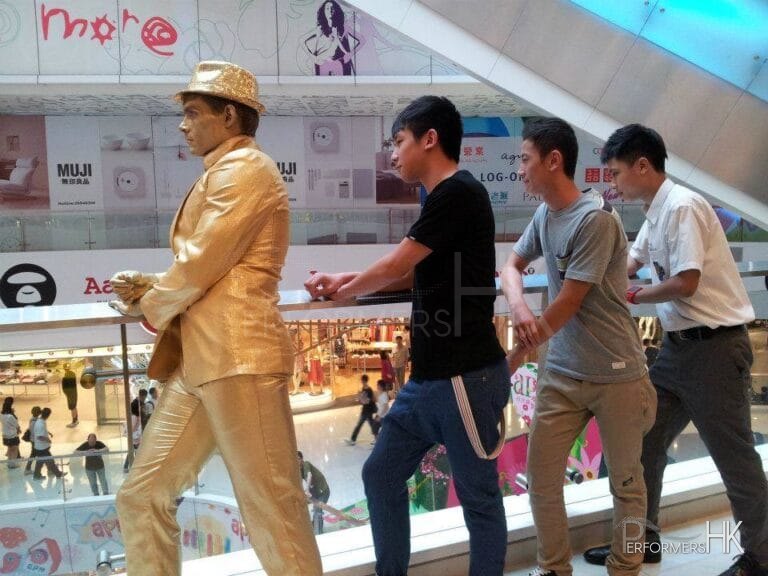 golden statue standing with 3 visitors in a shopping mall