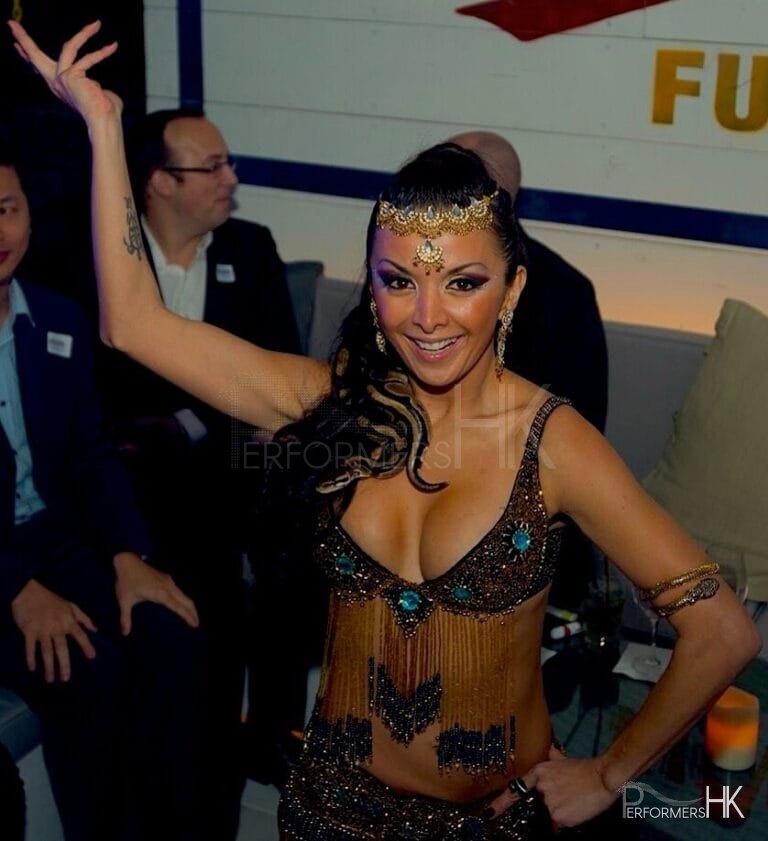 Female snake charm dancer poses with snake on her shoulder and performing in Hong Kong