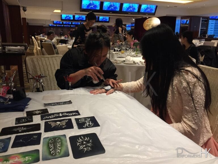 Take away and momentos temp tattoo artist spraying on a guests